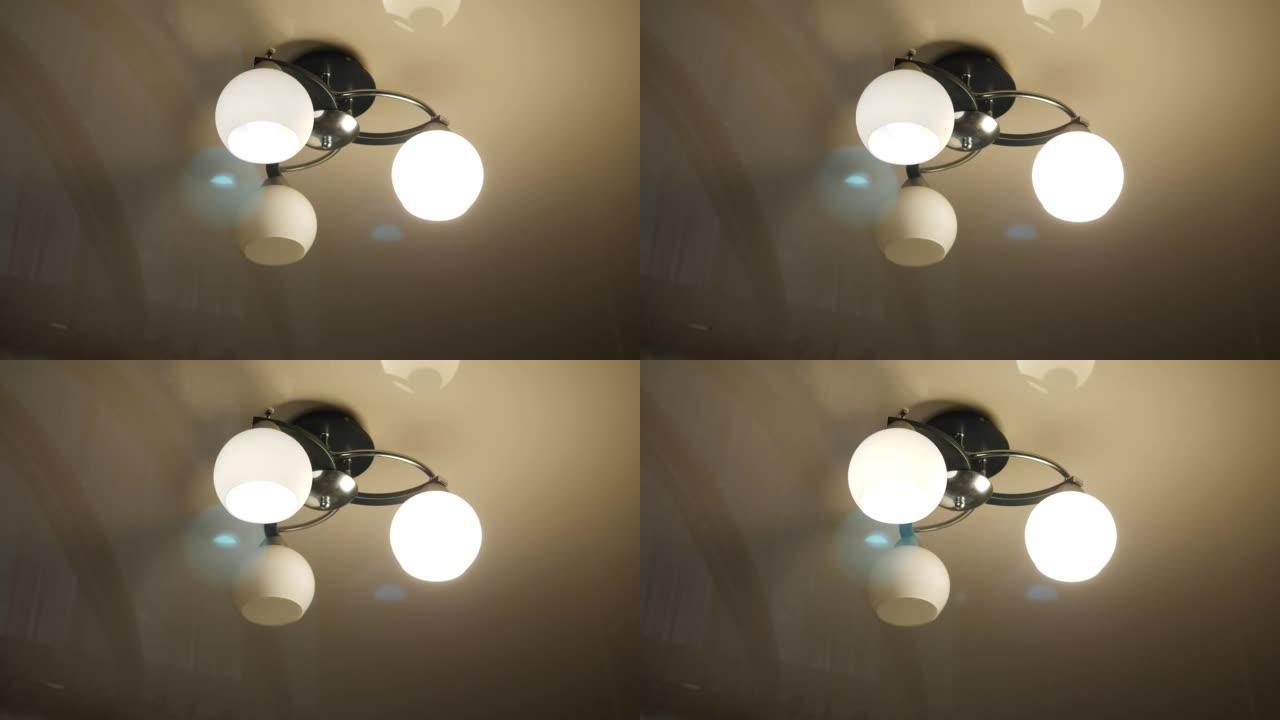 吊灯的特写镜头，天花板上有三盏灯，灯烧坏了。
