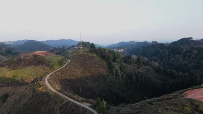 在覆盖着绿色森林和村庄的山顶上，电信塔的鸟瞰图。
