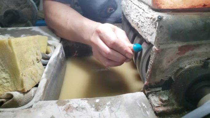 一位亚洲男子玛瑙工匠的手，他正在用金刚石砂轮机打磨和制作图案
