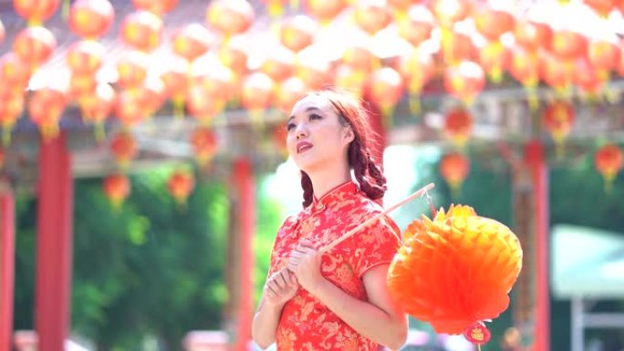 美丽年轻的亚洲妇女微笑着在中国传统的旗袍旗袍，拿着中国灯笼