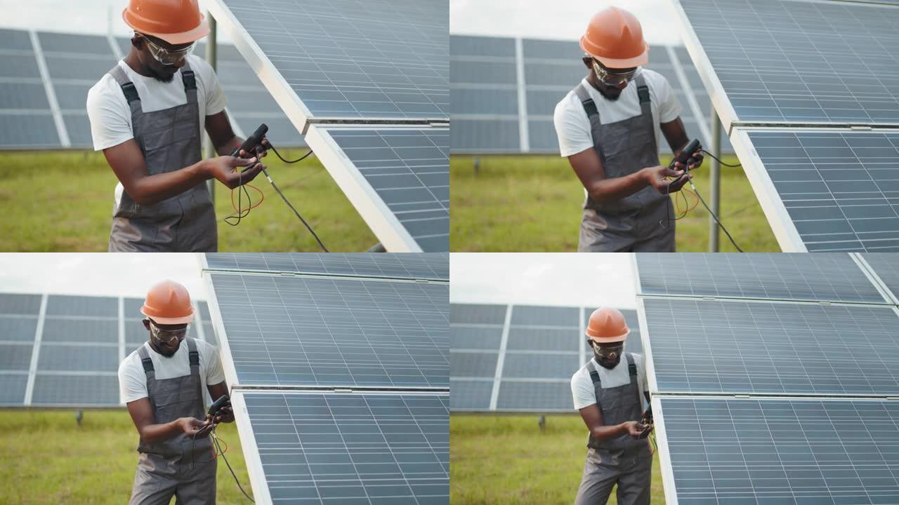 技术员统一使用万用表，同时检查太阳能电池板的电压。非裔美国人控制电站绿色能源的生产。穿着工作服的人测