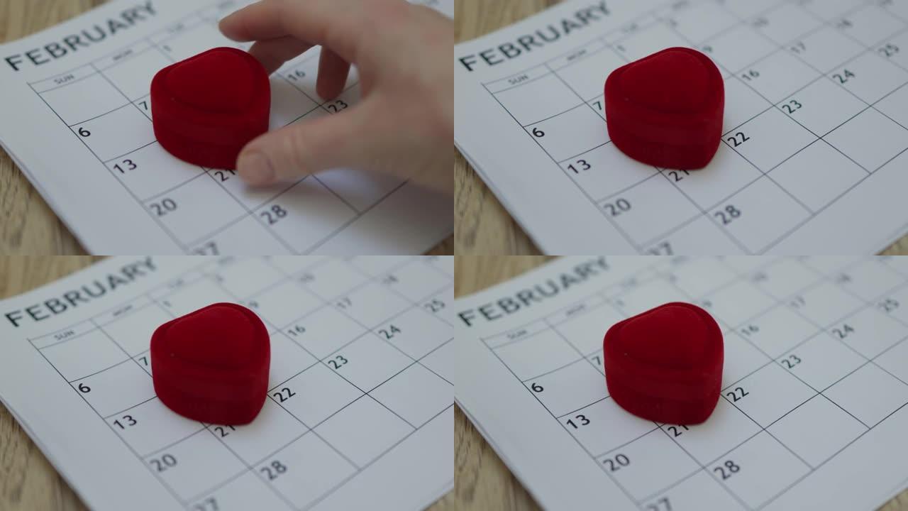 手工将心形红色戒指盒放在纸上月份日历2月14日日期