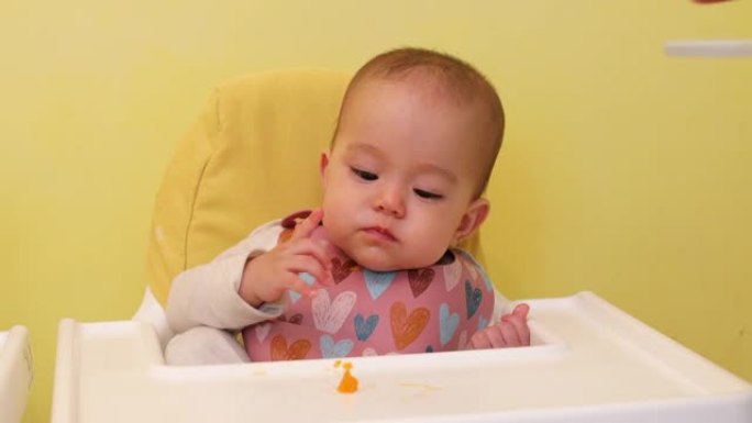 婴儿用手吃一块橘子的特写镜头