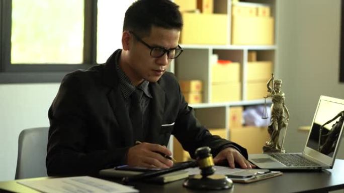 正义和法律的概念男性律师在办公室里工作，木桌上有一个铜秤女神。具有笔记本电脑法律概念和法律服务的ha