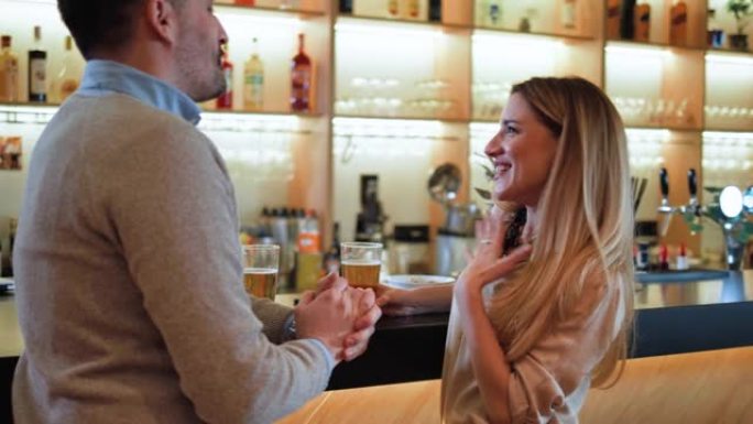 夫妇站在酒吧聊天和敬酒。男人和女人在酒吧放松喝啤酒