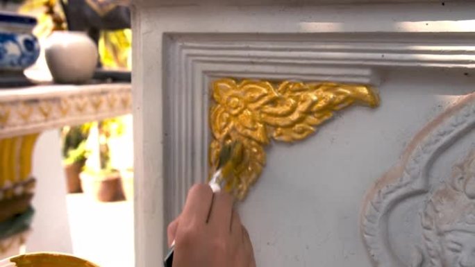 画家正在旧神社的元素上画金色。