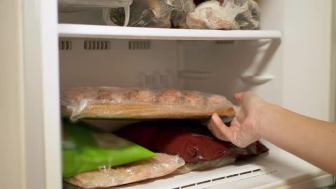 女性手将现成的半成品肉制品放入冰箱。特写