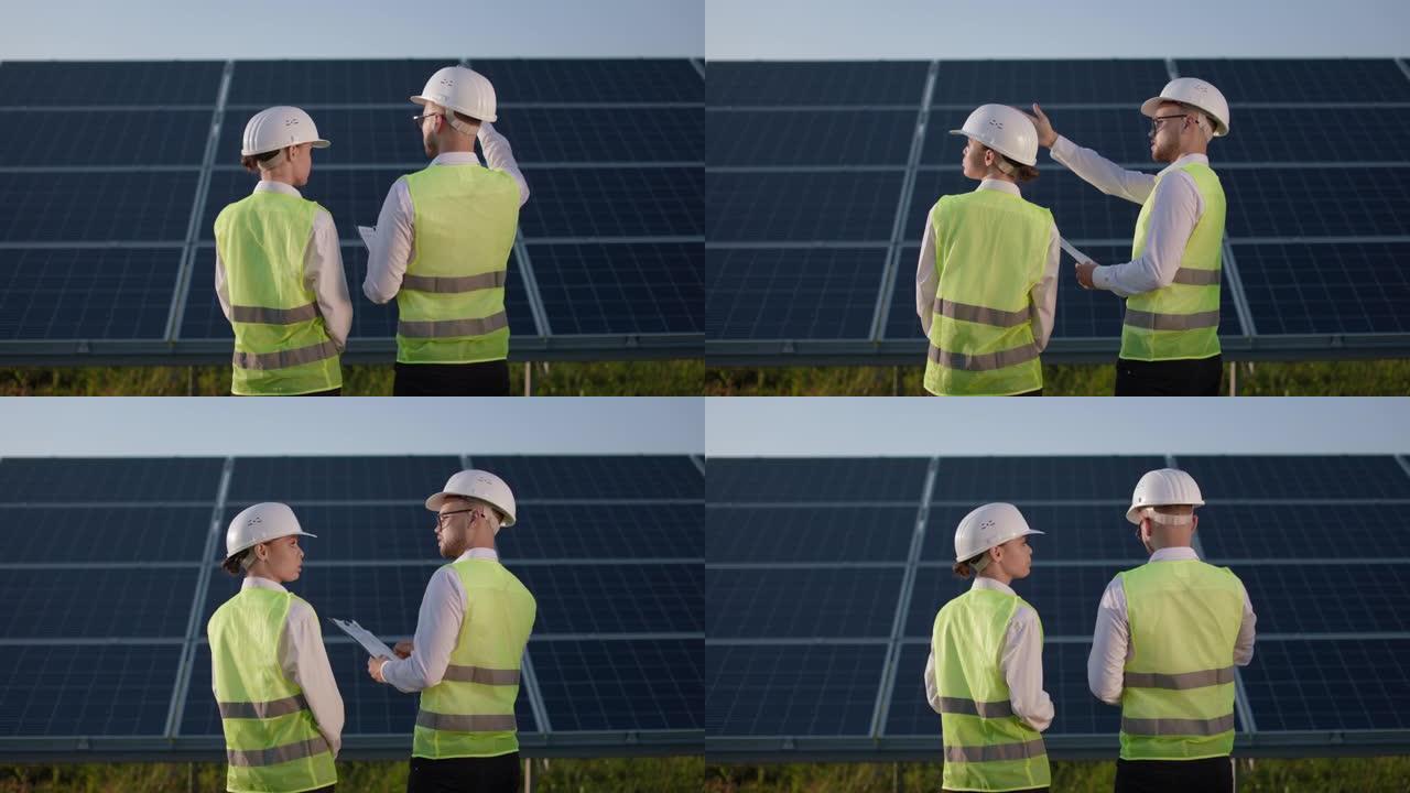 两名戴着头盔的技术人员一起站在太阳能站上。