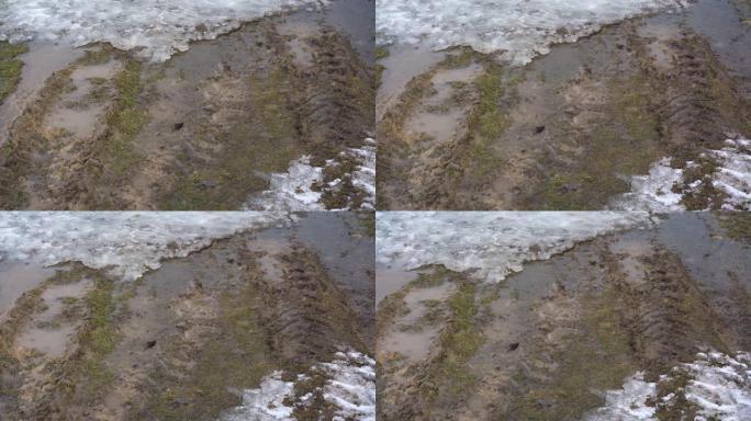 乡村道路上的积雪融化和泥泞的水坑无轨