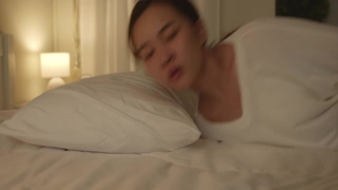 久经考验，疲惫不堪的年轻亚洲女子晚上躺在床上 (慢动作)
