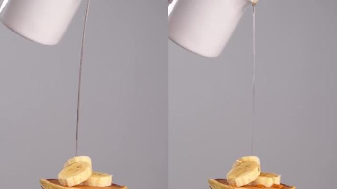 香蕉煎饼倒枫糖浆。慢动作，垂直镜头