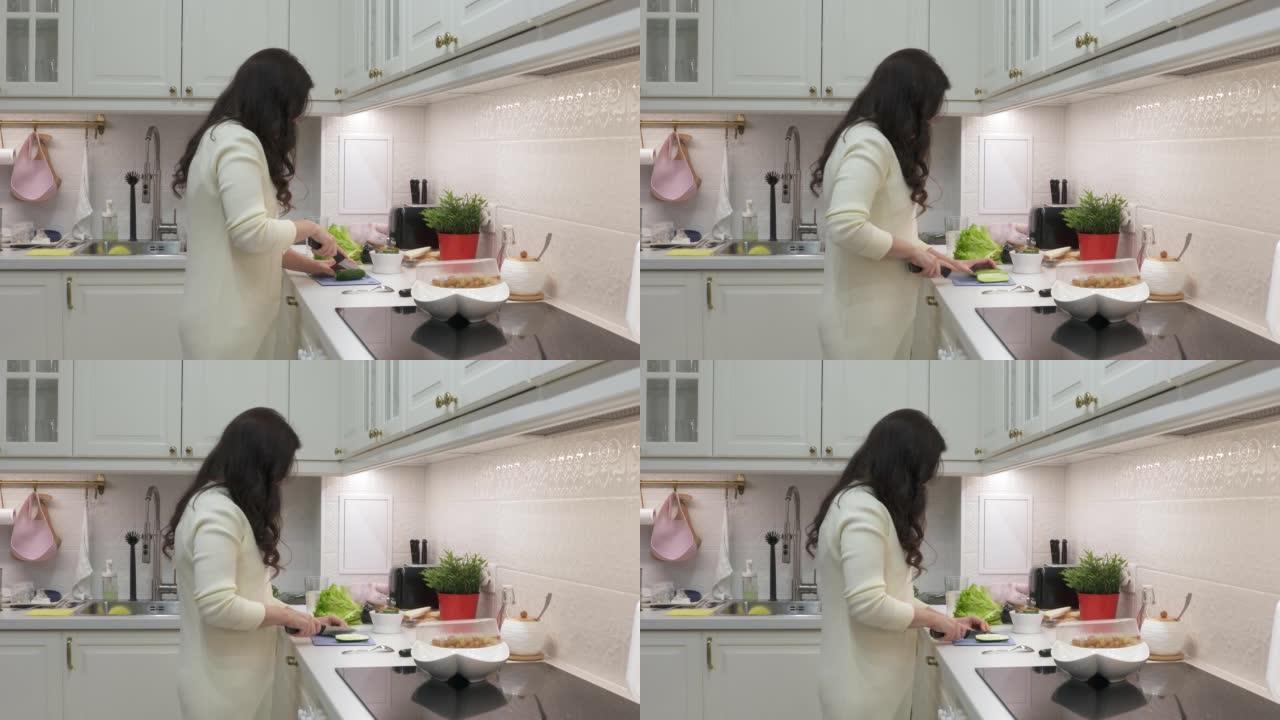 女人在厨房做饭，在厨房台面上切黄瓜。