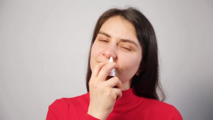 一名女性患者将喷雾剂推入鼻子以治疗鼻炎，这是一种呼吸困难的过敏