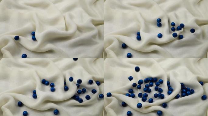 木制蓝色珠子在白色纺织品上滚动，背景，慢动作