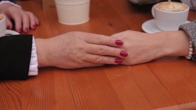 一位年老的皱纹妇女的手和她年幼的女儿的手。