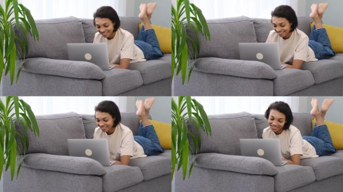自信的非洲裔美国女孩在智能手机上使用笔记本电脑，坐在家里的沙发上，复制空间
