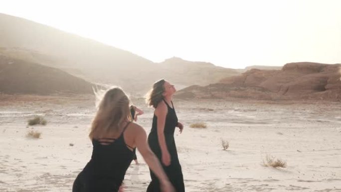 在日出的沙漠中，妇女们在多风的天气里练习狂喜的舞蹈