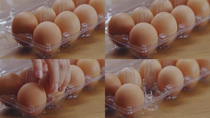 女人的手从一个塑料容器中取鸡蛋。
