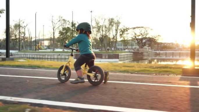 日落时骑平衡自行车的小女孩。