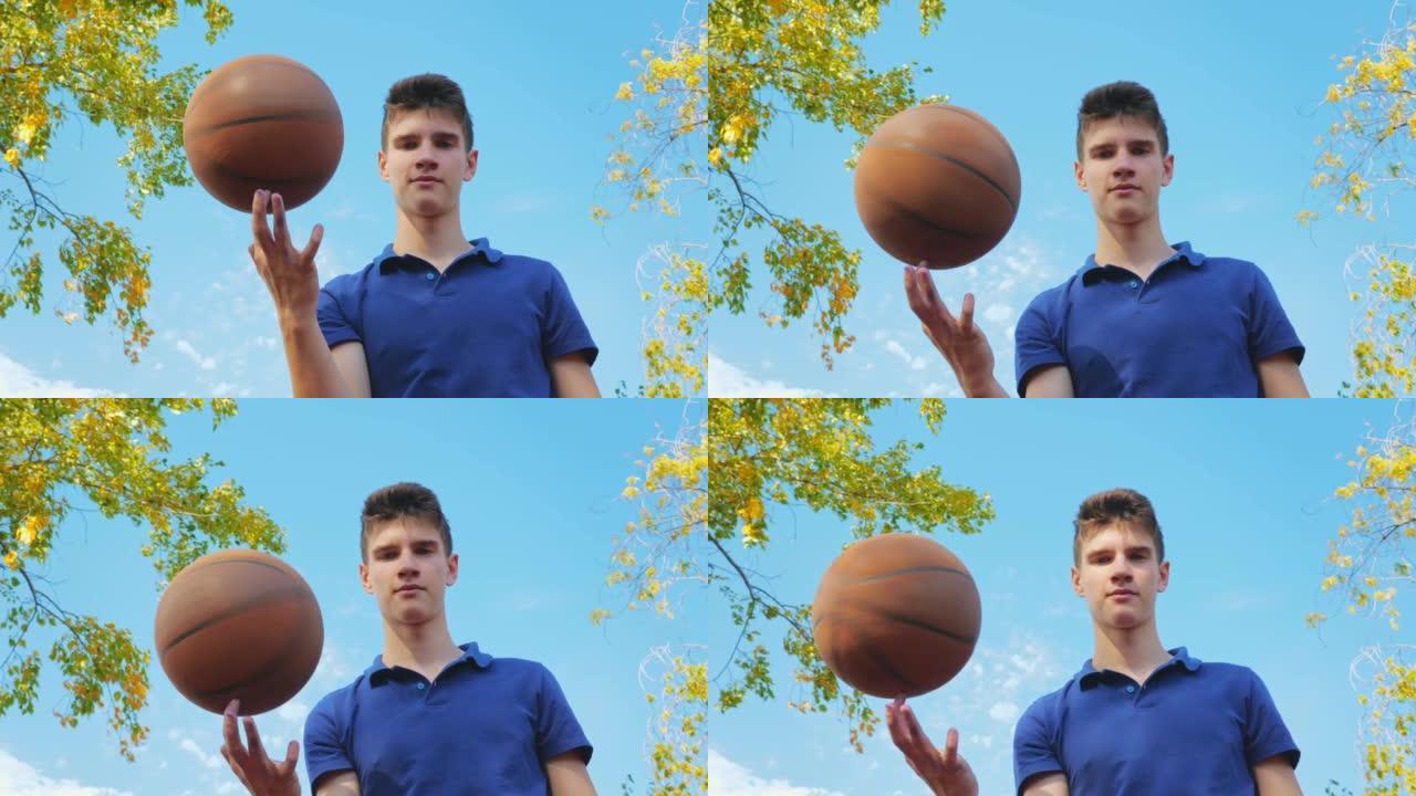 一个年轻的十几岁的男人在篮球场上时用手指旋转球。