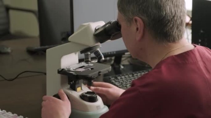 男性微生物学家，医务人员通过显微镜观察血液样本，并在实验室进行分析。实验室助理使用现代显微镜进行生物