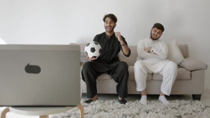 两名印度男子在现代房间观看足球