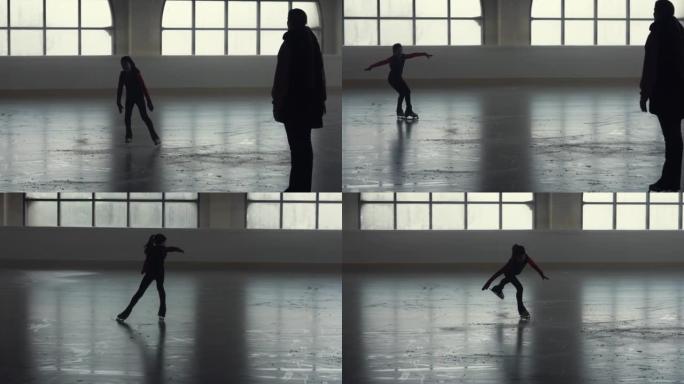 女教练教一个十几岁的女孩花样滑冰。小女孩运动员训练，在光线柔和的黑暗冰上竞技场上练习跳跃和旋转技巧。