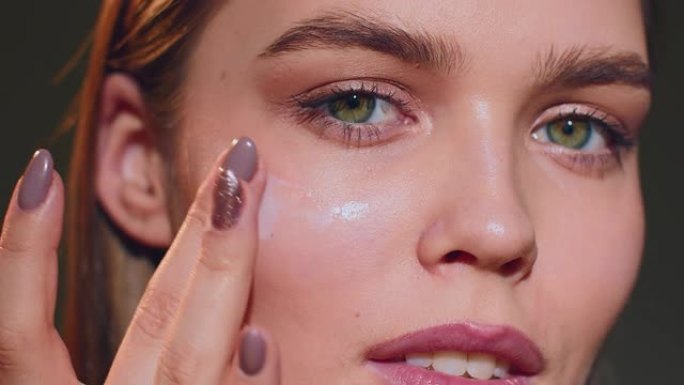 年轻女性将乳霜涂在眼睛周围的皮肤上。护肤护理化妆品广告。特写。普洛雷斯