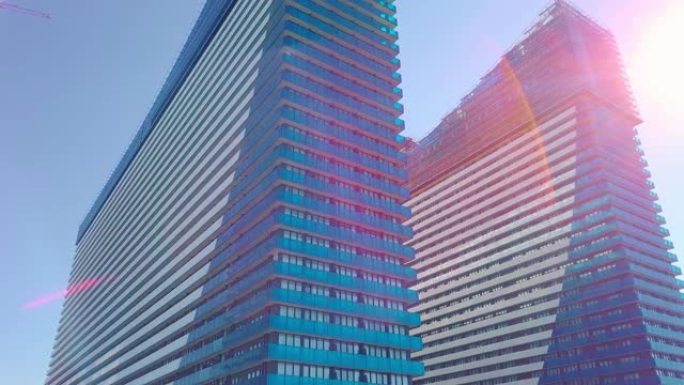 在城市摩天大楼的玻璃窗上拍摄太阳，云彩和天空的反射。