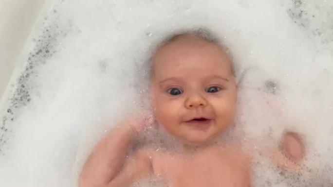 婴儿微笑着，在洗澡时很平静，然后突然被吓了一跳