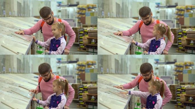 购物车里的父亲和小女孩在五金店里选择瓷砖。维修概念和建筑材料。购买商品进行维修