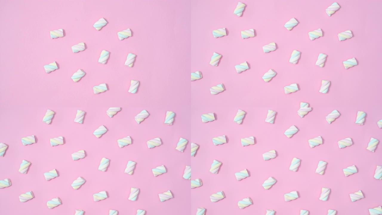 棉花糖糖果在柔和的粉红色背景上制作图案。停止运动平铺