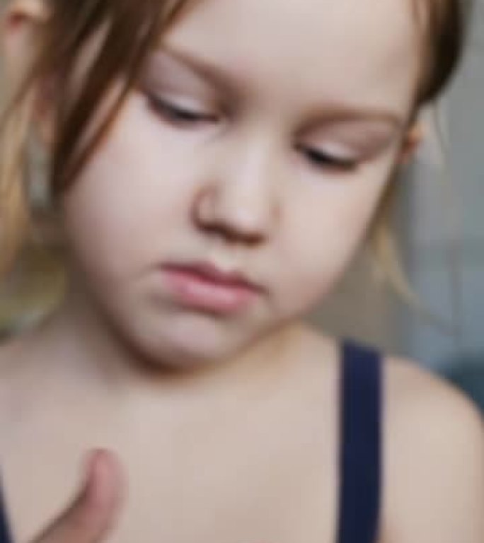 肖像: 一个十几岁的女孩拿起用过的口香糖，手指粘在一起。孩子仔细检查粘在手指上的口香糖，并试图释放双