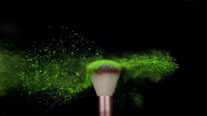 黑色背景上绿色粉末爆炸的化妆刷超慢动作