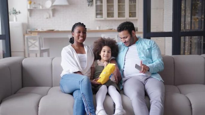 快乐的年轻家庭拥抱沙发在客厅看电视
