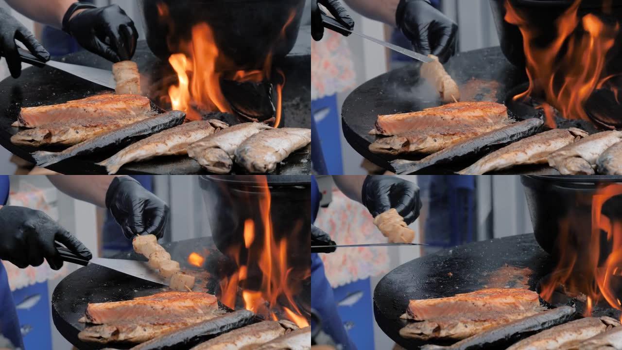 厨师在黑色火盆上烹饪扇贝肉、鲑鱼、臭鱼 -- 特写