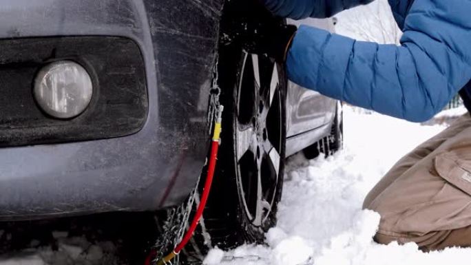 汽车被困在雪地里，男人在轮胎上放了防滑链