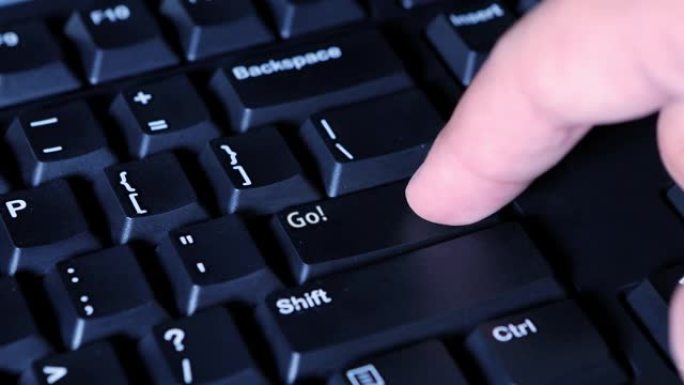 男性手指按下电脑键盘上的Go按钮
