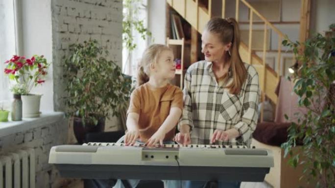 单身母亲和她的小女儿在演奏合成器时互相看着对方并互相微笑