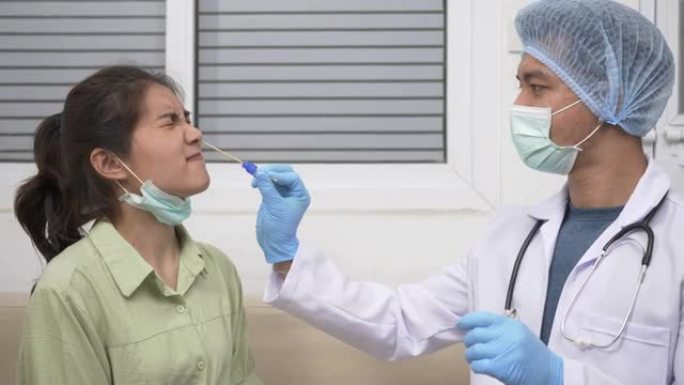 医生用棉签通过鼻子采集唾液样本，检查亚洲年轻女子的冠状病毒测试