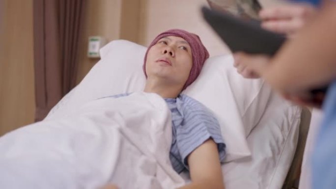 戴着头饰并躺在病床上的男性患者的低角度镜头集中了他的症状和疾病，这是从医生在医院病房拿着x光片进行检