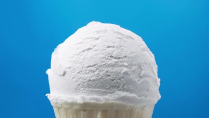 旋转香草冰淇淋在蓝色背景下的圆锥形。食品概念。
