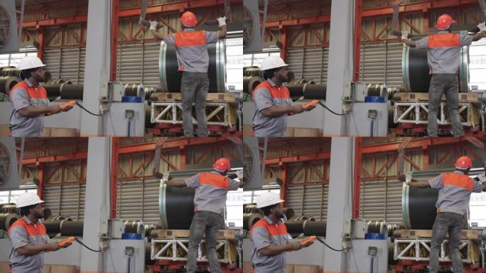 一家工业工厂的两名非洲工人一起工作，带来钢钩来提升板材卷。