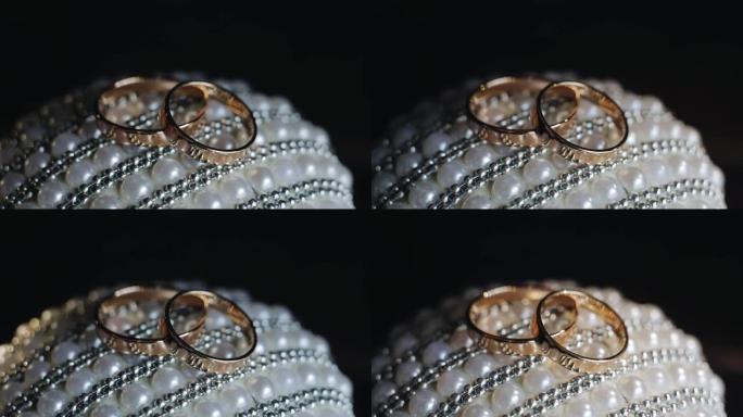 两个金戒指被特写拍摄，并被动态光照亮。灯光下的花式图案