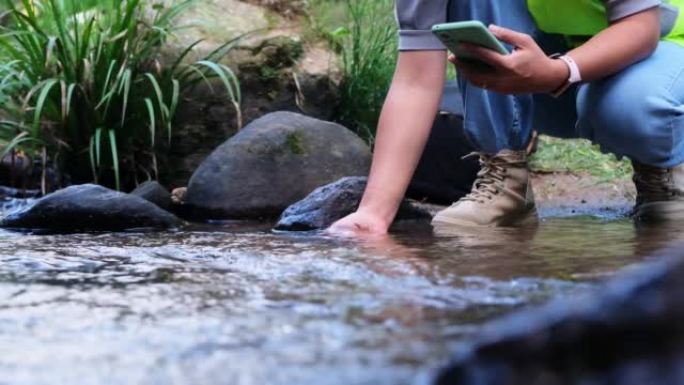 环境工程师检查天然水源的水质，并在智能手机上记录数据。女科学家和环境问题。世界环境日概念。