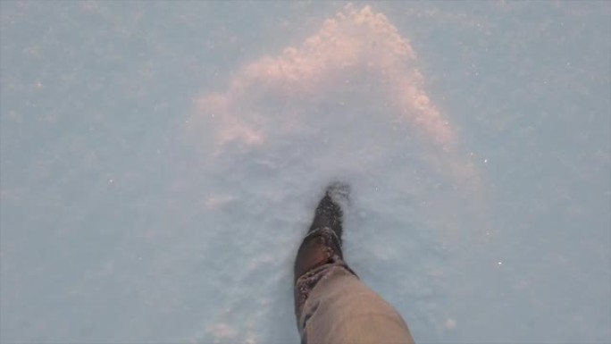 男人的腿在阳光下在雪地上行走。脚在深雪中行走。高质量全高清镜头。