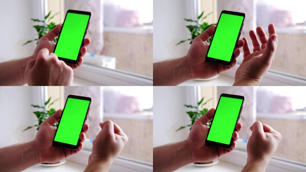 男性双手手持绿屏手机。用手指指着它。误解，失望的姿态。