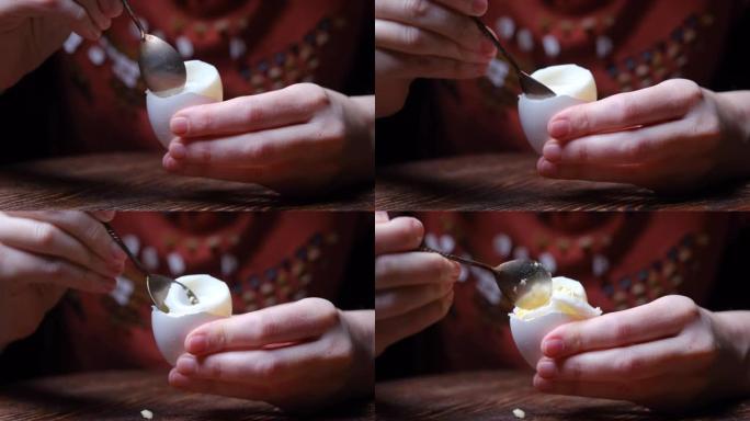 人类的手正在用茶匙煮鸡蛋