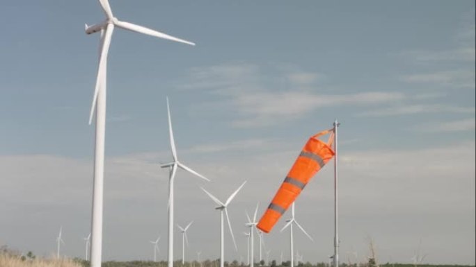 风车在风力涡轮机领域旋转，具有橙色风袜，绿色能源和可再生能源概念