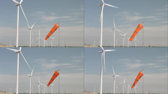 风车在风力涡轮机领域旋转，具有橙色风袜，绿色能源和可再生能源概念